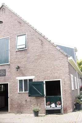 a brick building with two windows and two potted plants at Apartment Het Friesche Paard in Purmer