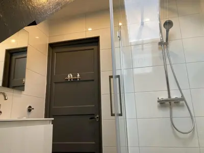 a shower with a black door in a bathroom at Apartment Het Friesche Paard in Purmer