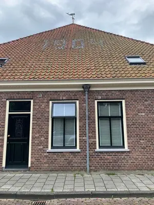 a brick house with a red roof and two windows at 