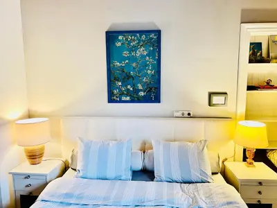 a bedroom with a bed with a blue painting above it at 