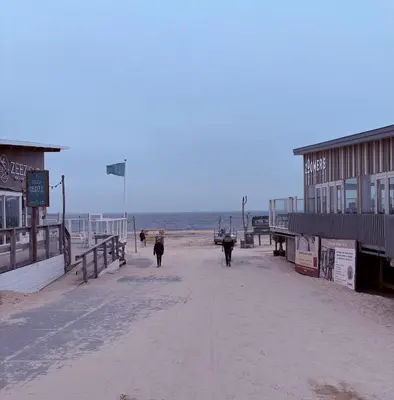 two people walking down a beach with the ocean at 