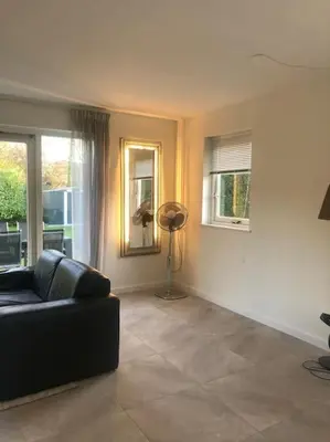 a living room with a black couch and windows at Strand Villa Stern Noordwijk in Noordwijk