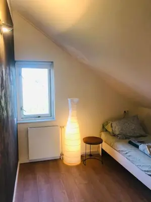 a room with a bed and a lamp next to a window at Strand Villa Stern Noordwijk in Noordwijk