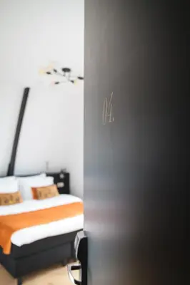 a bedroom with a bed with orange sheets and pillows at Boutique Hotel 43 Amsterdam - Zaandam in Koog aan de Zaan