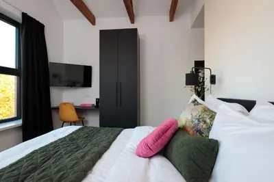 a bedroom with a white bed with pink pillows on it at Boutique Hotel 43 Amsterdam - Zaandam in Koog aan de Zaan