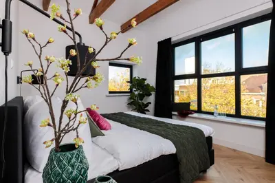 a bedroom with a bed with a vase with flowers at Boutique Hotel 43 Amsterdam - Zaandam in Koog aan de Zaan