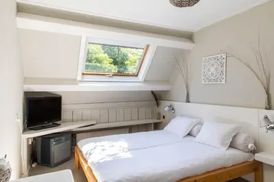 a bedroom with a bed and a tv and a window at Hotelroom Villa 1913 in Bergen