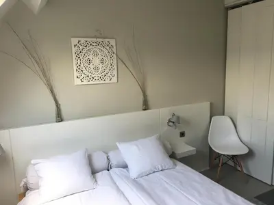 a bedroom with a bed with white pillows and a chair at Hotelroom Villa 1913 in Bergen