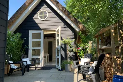 a small house with chairs and a patio at Bergen, Huisje dat ademt zee en vakantie... in Bergen