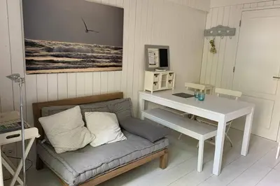 a living room with a couch and a white table at Bergen, Huisje dat ademt zee en vakantie... in Bergen