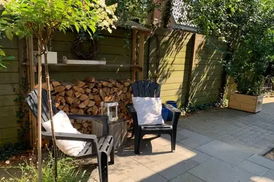 two chairs sitting next to a pile of fire wood at Bergen, Huisje dat ademt zee en vakantie... in Bergen