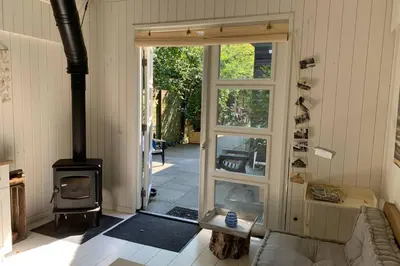 a living room with a wood stove and an open door at Bergen, Huisje dat ademt zee en vakantie... in Bergen