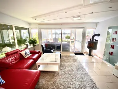 a living room with a red couch and a table at Ferienhaus mit wundervollem Seeblick Ferienpark Vislust Ijsselmeer in Wervershoof