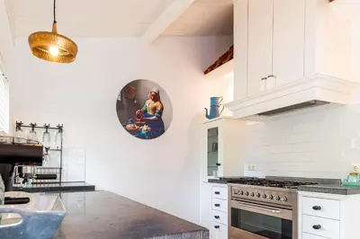 a kitchen with white cabinets and a clock on the wall at Gastenverblijf KortVertoef in Kortenhoef