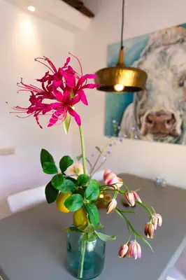 a pink flower in a vase on a table at Gastenverblijf KortVertoef in Kortenhoef