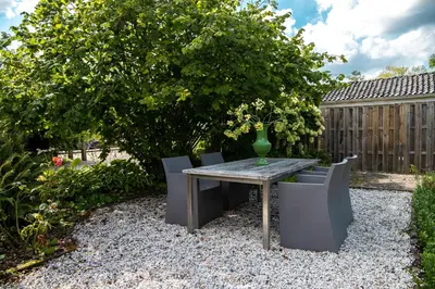 a table and chairs in a garden with a vase on it at Gastenverblijf KortVertoef in Kortenhoef