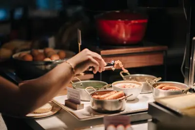 a person is preparing food in pots on a table at Hotel Omega in Amsterdam
