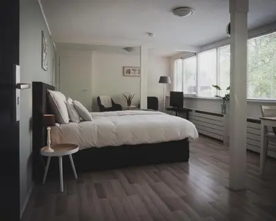 a bedroom with a bed and a table and a desk at B&B Het Ruime Sop in Wassenaar
