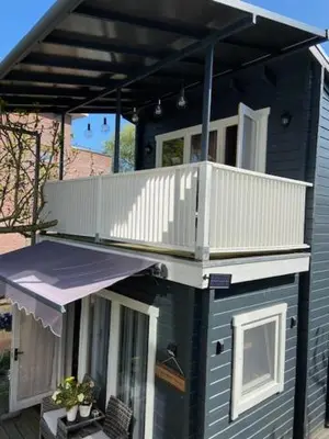 a small house with a balcony and a deck at Tinyhouse Woody at the Water in Zaandam