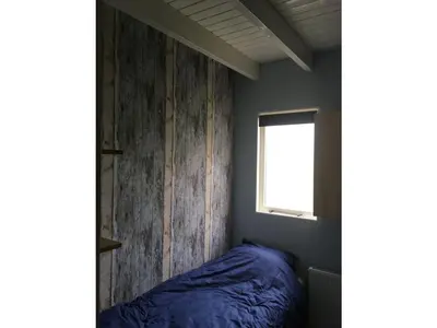 a bedroom with a blue bed and a window at Vakantiewoning Van der Meer, Egmond aan Zee in Egmond aan Zee