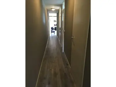 a hallway with a long wooden floor in a room at Vakantiewoning Van der Meer, Egmond aan Zee in Egmond aan Zee