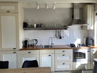 a kitchen with white cabinets and a sink at Vakantiewoning Van der Meer, Egmond aan Zee in Egmond aan Zee