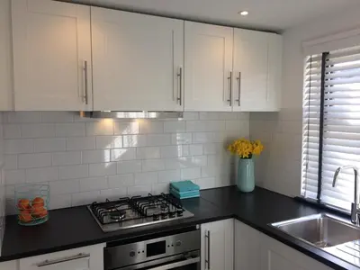 a kitchen with white cabinets and a stove top oven at Zomerhuis Zuid 1 in Egmond aan Zee