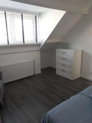 an attic bedroom with a bed and a dresser and two windows at Zomerhuis Zuid 1 in Egmond aan Zee