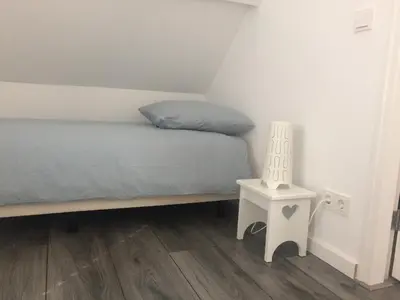 a bedroom with a bed and a side table at Zomerhuis Zuid 1 in Egmond aan Zee