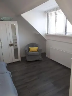a living room with a chair with a yellow pillow at Zomerhuis Zuid 1 in Egmond aan Zee