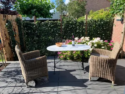 a patio with a table and two chairs and flowers at Jagershof in Egmond aan den Hoef