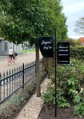 two signs next to a fence next to a tree at Jagershof in Egmond aan den Hoef