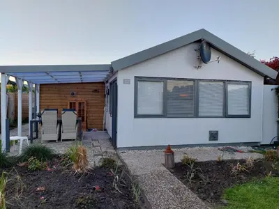 a white house with a porch and a patio at Cottage 322 in Dirkshorn