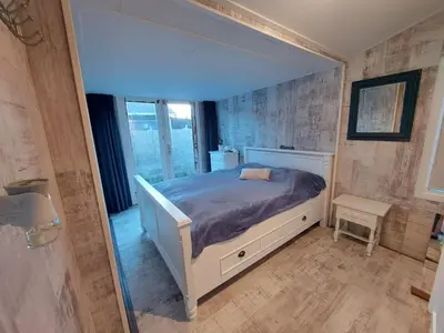 a bedroom with a bed and a mirror at Cottage 322 in Dirkshorn