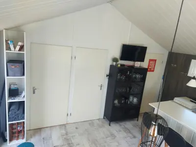 a living room with white cabinets and a tv at Cottage 322 in Dirkshorn
