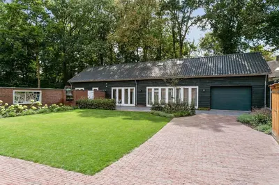 a brick house with a garage and a grass yard at Bed & Breakfast De Oude Kapel in Driebergen