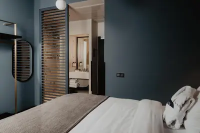 a bedroom with blue walls and a bed and a bathroom at The Nox Hotel in Utrecht