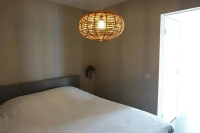 a bedroom with a white bed and a chandelier at Vakantie huis aan het water in Rijpwetering