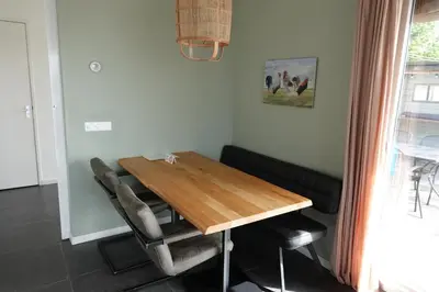 a dining room with a wooden table and chairs at Vakantie huis aan het water in Rijpwetering
