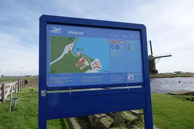 a sign in a field with a windmill in the background at Vakantie huis aan het water in Rijpwetering