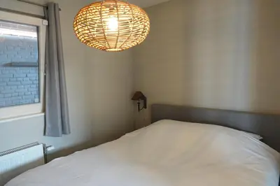 a bedroom with a bed and a chandelier at Vakantie huis aan het water in Rijpwetering