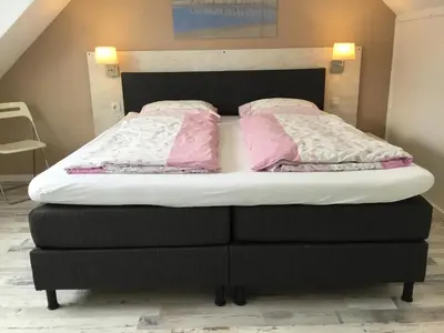 a bed with two pink pillows on top of it at De Linden in Egmond aan Zee