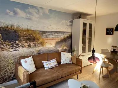 a couch in a living room with a beach mural at De Linden in Egmond aan Zee