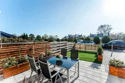 a patio with a table and chairs and a fence at Green Happiness With Private Parking in Zandvoort
