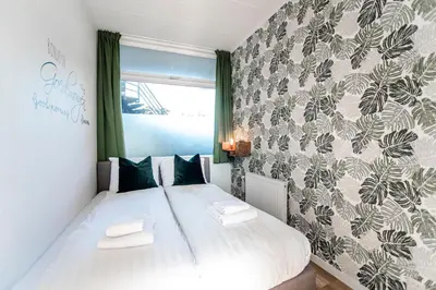 a bedroom with a large white bed and a wall at Green Happiness With Private Parking in Zandvoort