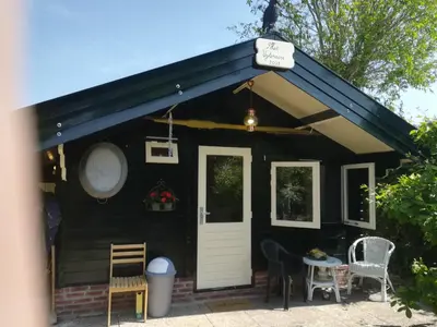 a black house with a white door and a table and chairs at het Uylennest, uniek en goedkoop! in Hem