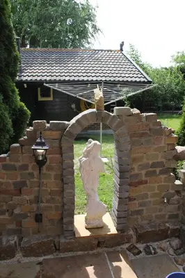 a stone archway with a statue in front of a building at het Uylennest, uniek en goedkoop! in Hem