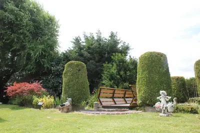a park with a bench and some statues in the grass at het Uylennest, uniek en goedkoop! in Hem