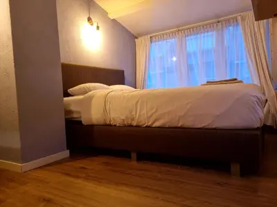 a bedroom with a large bed with a window at cottage near the beach in the center.**** in Noordwijk aan Zee