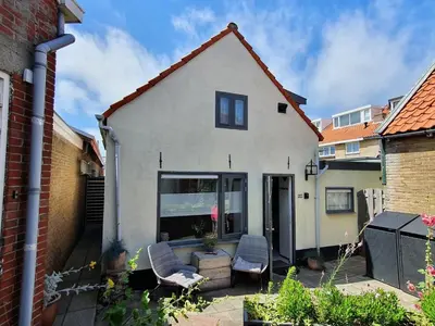 a white house with two chairs in a yard at cottage near the beach in the center.**** in Noordwijk aan Zee